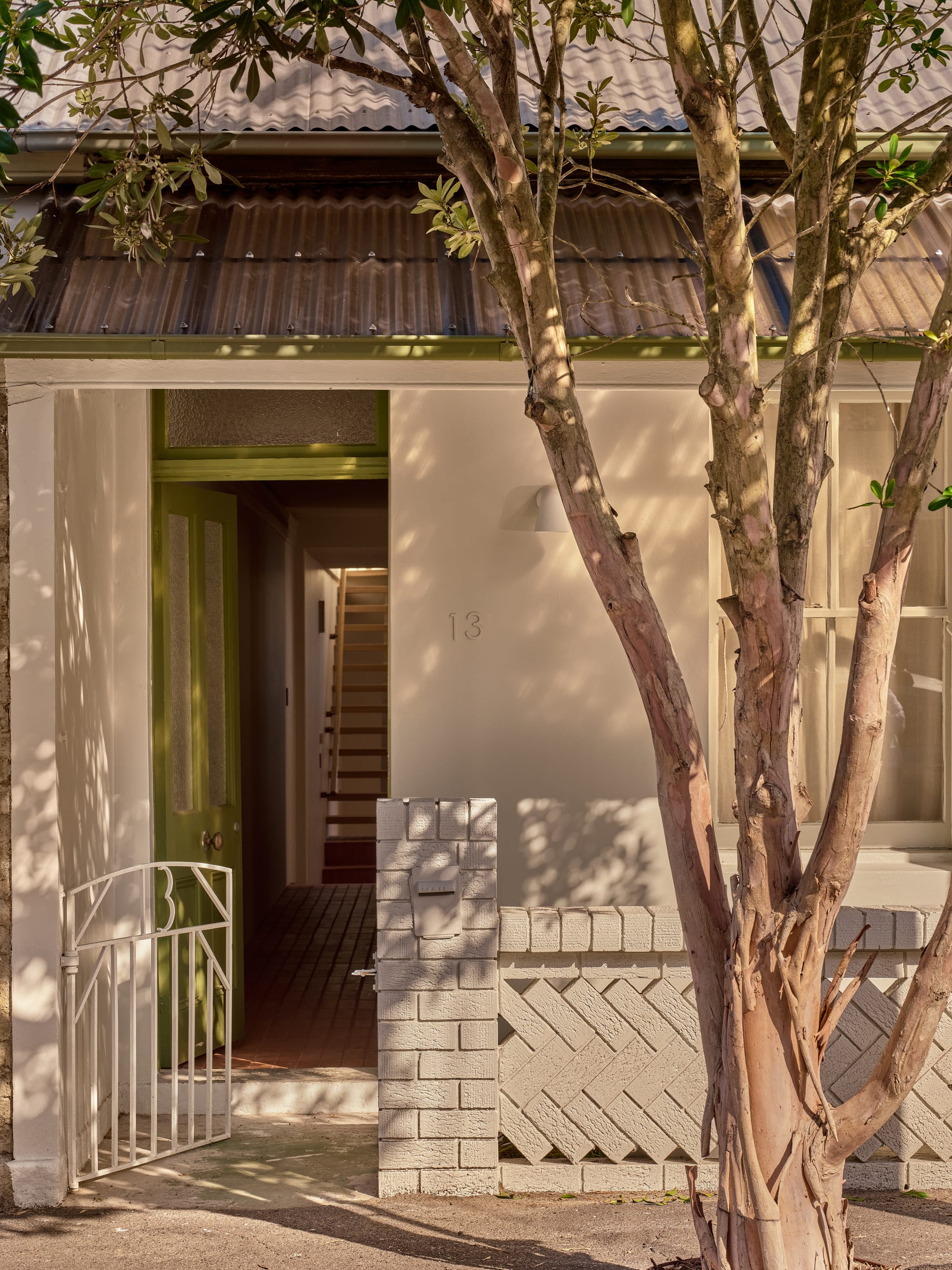Birchgrove heritage terrace facade with corrugated iron awning, an olive-green door and painted brick fence